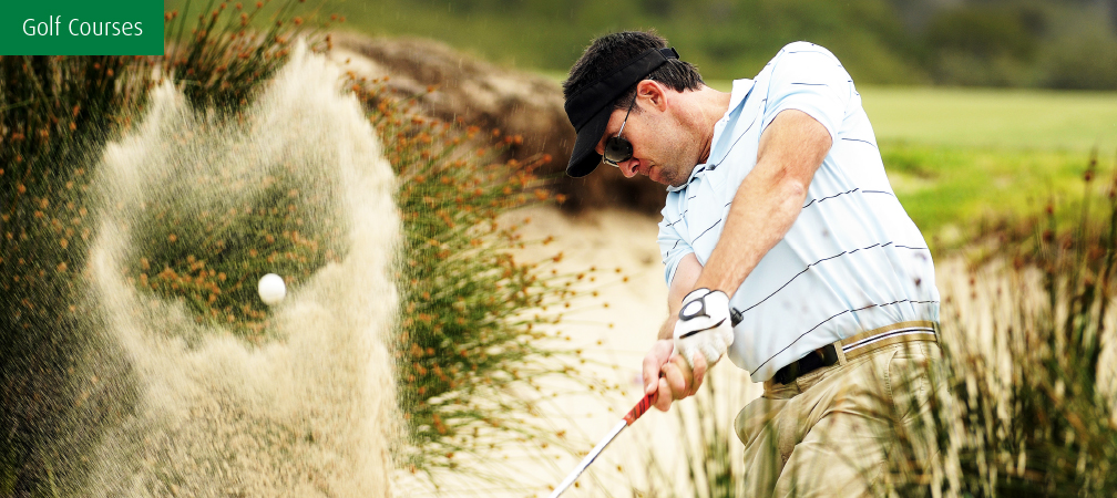 golfer tee shot from sand bunker