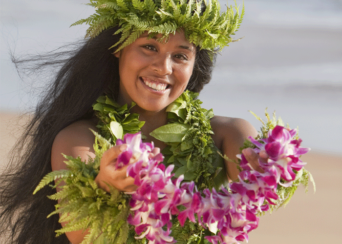 Hawaii hula girl with leis smiling for the camera.